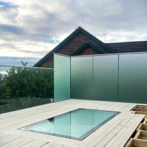 Frameless glass balcony surrounding a rooftop skylight with privacy glass panels, installed by Colourglass Glazing.