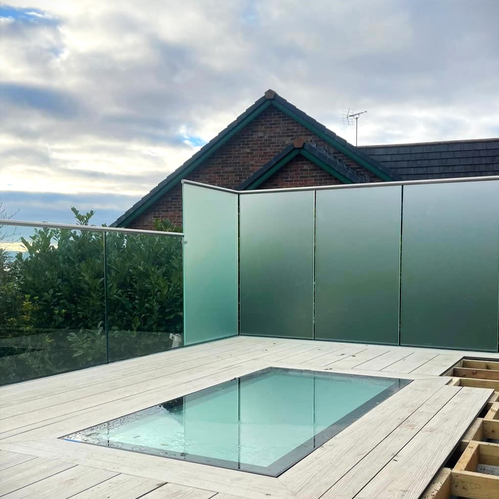 Frameless glass balcony surrounding a rooftop skylight with privacy glass panels, installed by Colourglass Glazing.